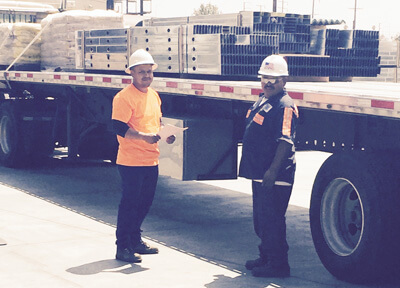 two men in hard hats next to truck full of metal framing studs